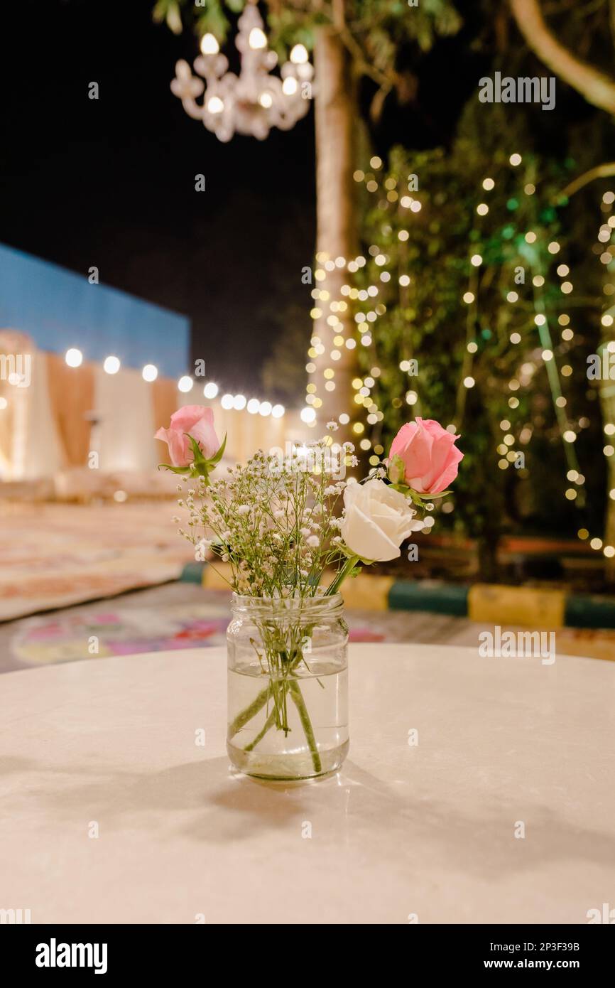 Ein farbenfroher Strauß frisch geschnittener Blumen in einer transparenten Glasvase auf einem Tisch Stockfoto