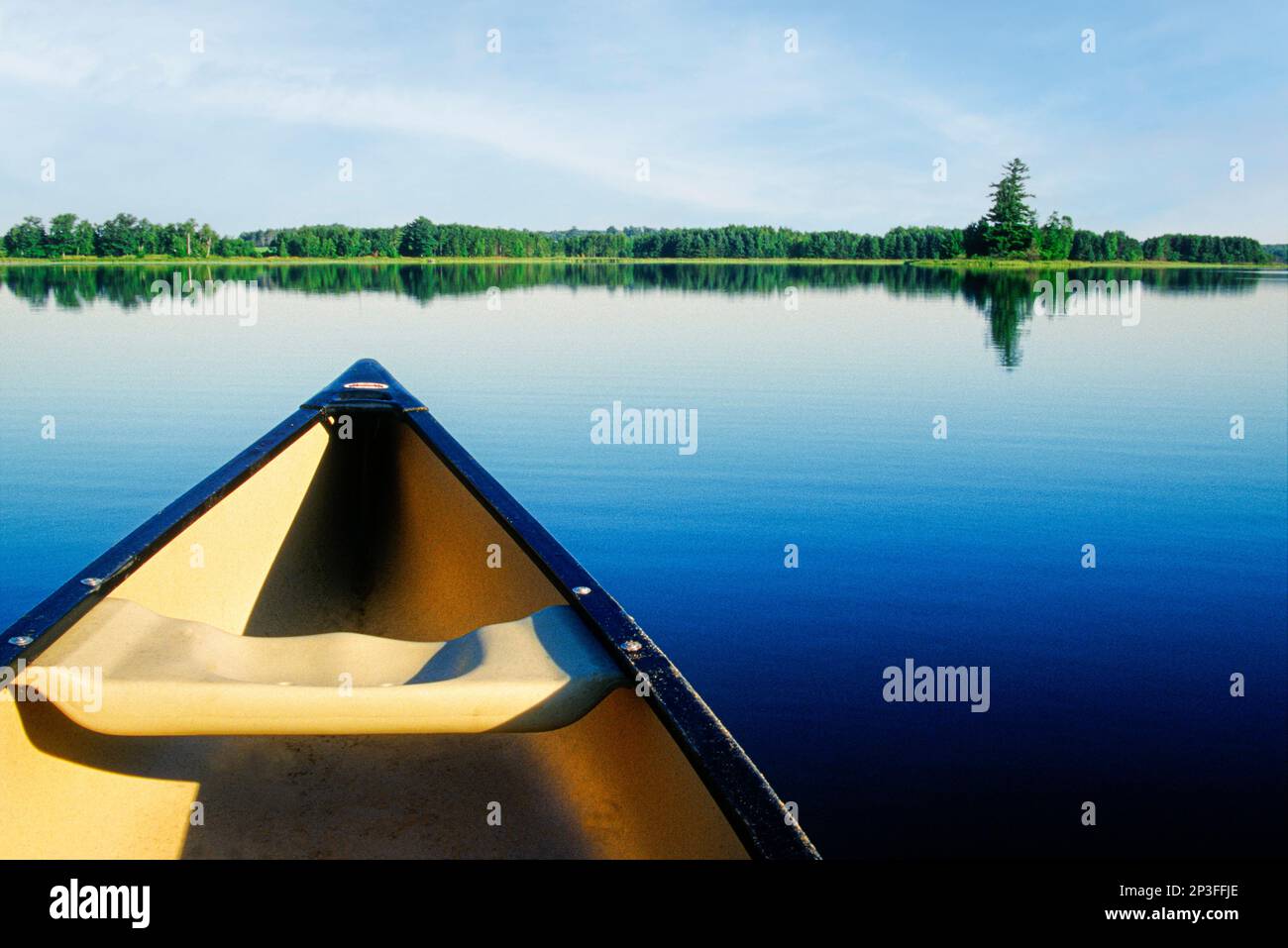 Morgens fährt ein Kanu über einen ruhigen See in Minnesota. Stockfoto
