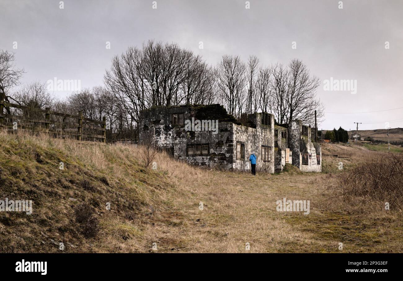 Eine Frau schaut in das Fenster der ehemaligen Horse and Jockey Pub Ruin im Troak Hey NOOK, Castleshaw bei Standedge, Saddleworth Stockfoto