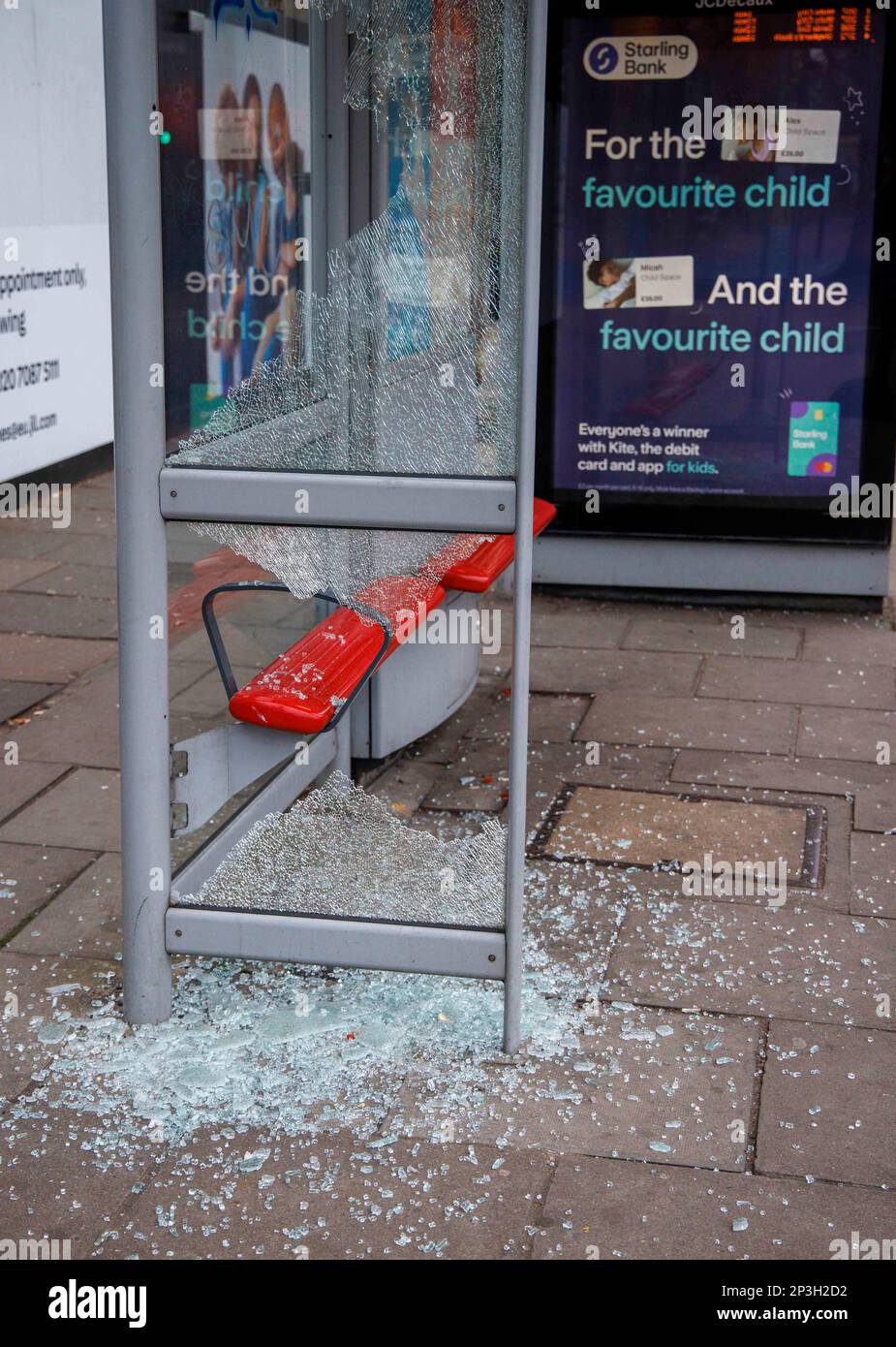 Ein verwundeter Busbunker in Acton Town London. Zerbrochenes Glas liegt auf dem Bürgersteig, als zwei Glasscheiben zertrümmert wurden. Stockfoto