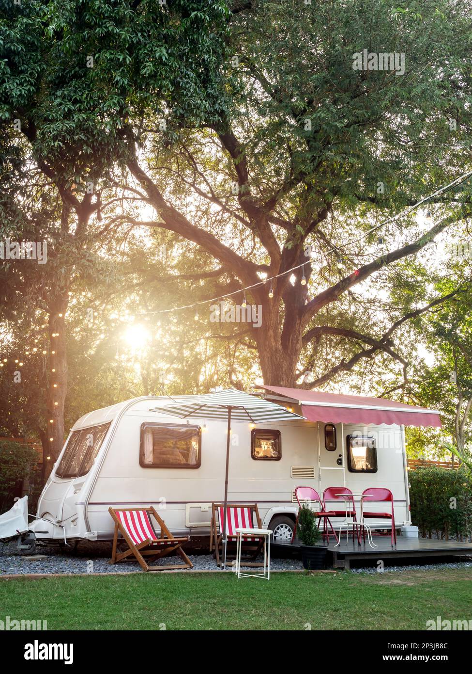 Parkhaus im Vintage-Stil im Garten mit leeren Sitzen und Tisch auf einem großen Baumhintergrund, vertikaler Stil. Entspannen Sie sich beim Camping und schlafen Sie im Mott Stockfoto