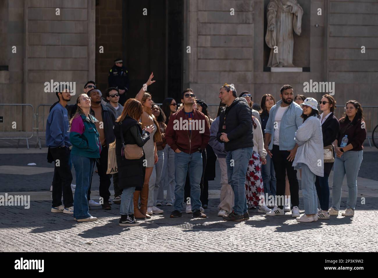 Eine Gruppe von Personen, die an der Plaza de Sant Jaume gesehen wurden und die Erläuterungen eines Reiseleiters in einer Gruppe erhielten. Am 1. März trat das kommunale Dekret in Kraft, das festlegt, dass geführte Reisegruppen durch das historische Zentrum von Barcelona nicht mehr als 20 Personen umfassen dürfen. Ferner wird das Verbot der Verwendung von Lautsprechern und der Überschreitung der Kapazität von Gruppen auf einigen Straßen und Plätzen eingeführt. Stockfoto