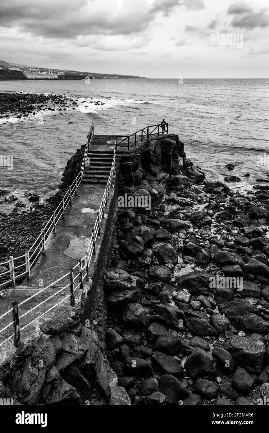 Pier neben dem kleinen Hafen in Punta del Hidalgo auf Teneriffa mit der Küstenstadt Bajamar im Hintergrund. Stockfoto