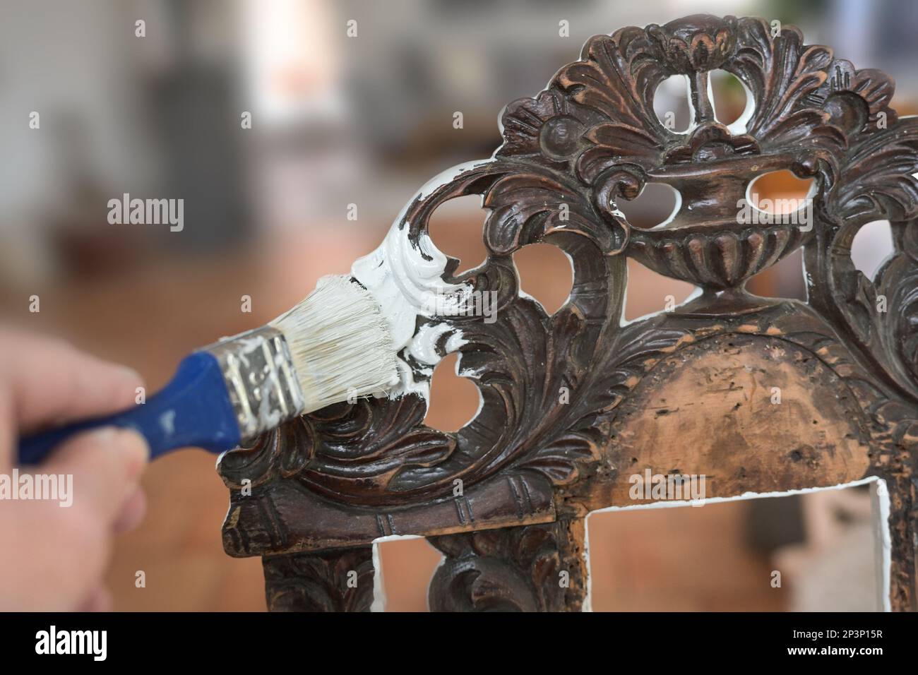 Einen alten Stuhl aus dunklem Holz mit einem Pinsel und einer weißen Farbe streichen, um Möbel in schäbigem, schicken Stil zu bekommen, hausgemachtes Innendesign Stockfoto Einen alten Stuhl aus dunklem Holz mit einem Pinsel und einer weißen Farbe streichen, um Möbel in schäbigem, schicken Stil zu bekommen, hausgemachtes Innendesign Stockfoto