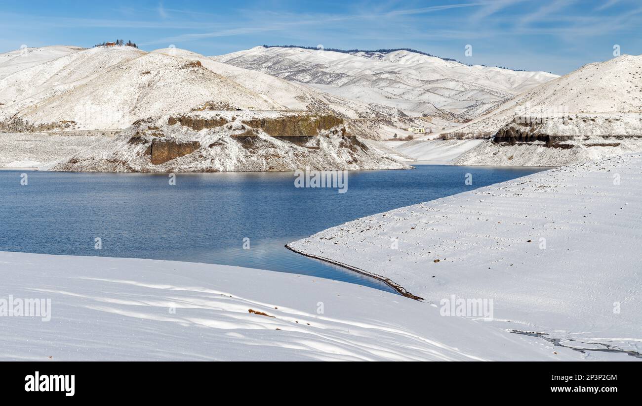 Reservoir mit niedrigem Wasser im Winter mit weißem Schnee und blauem Himmel Stockfoto