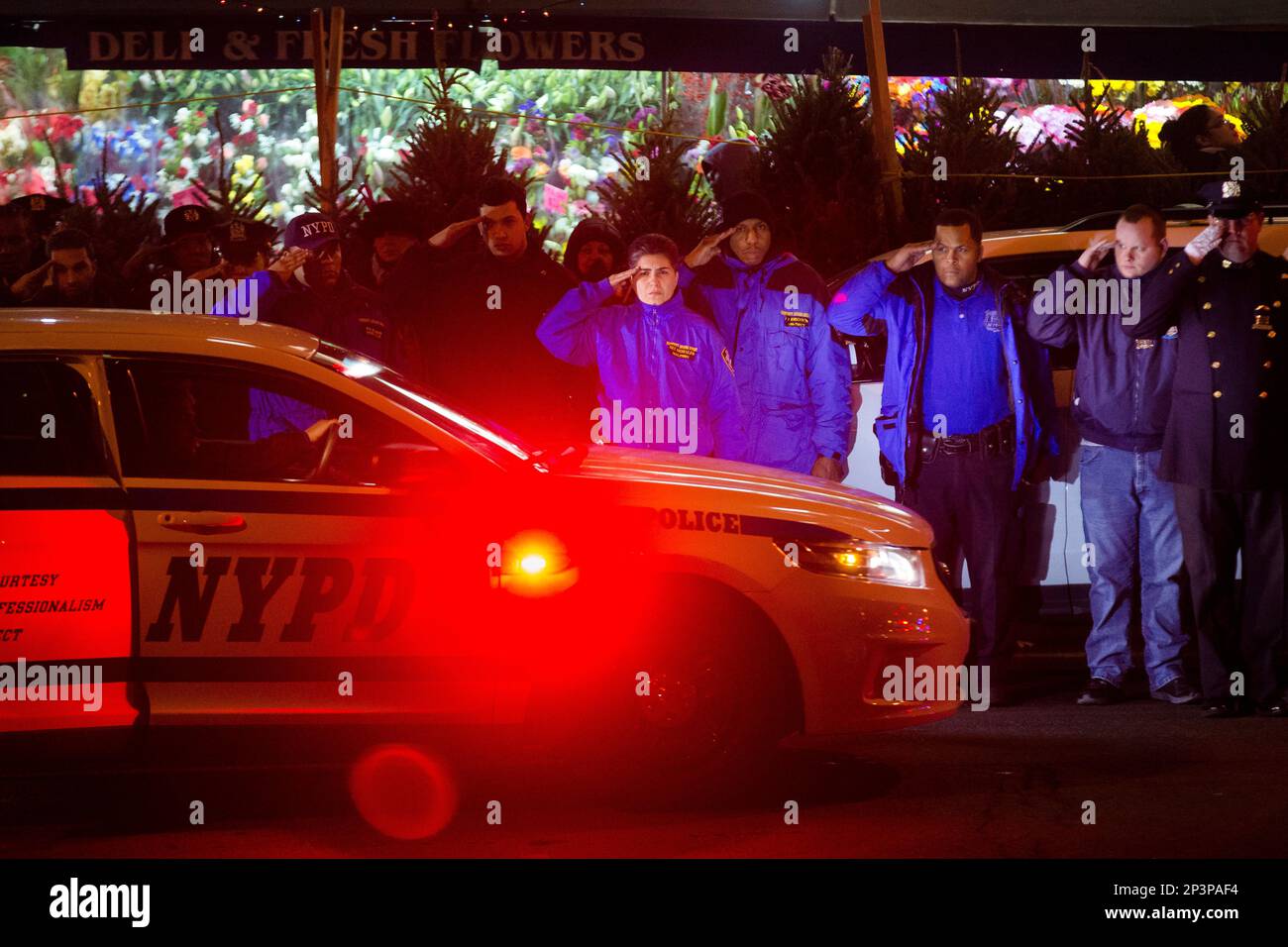 ADDS BOTH OFFICERS KILLED - Mourners stand at attention as the bodies of two fallen NYPD police officers are transported from Woodhull Medical Center, Saturday, Dec. 20, 2014, in New York. An armed man walked up to two New York Police Department officers sitting inside a patrol car and opened fire Saturday afternoon, killing both officers before running into a nearby subway station and committing suicide, police said. (AP Photo/John Minchillo) Stockfoto