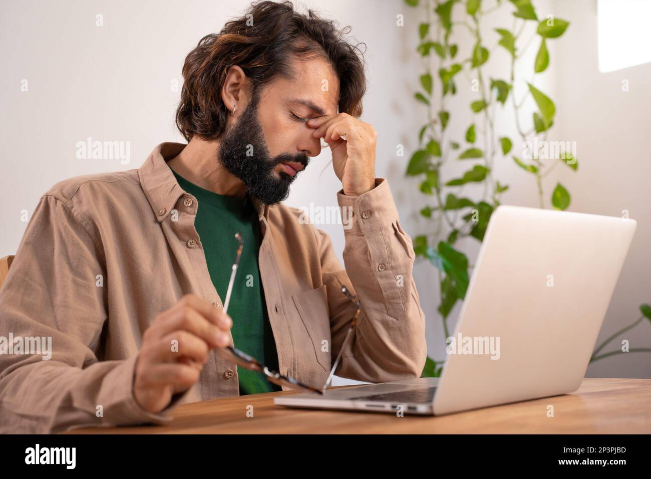 Gestresster müder Geschäftsmann mit Kopfschmerzen vor dem Computer. Stockfoto
