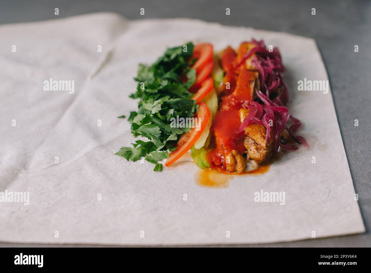 Shawarma-Vorbereitung. Fleisch, Gemüse und Soße auf Pita-Brot. Stockfoto