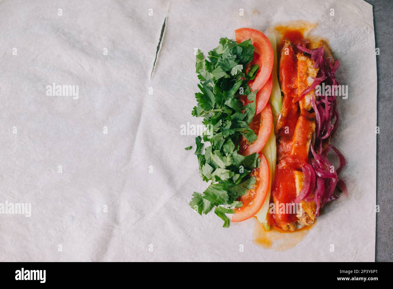 Shawarma-Vorbereitung. Fleisch, Gemüse und Soße auf Pita-Brot. Stockfoto