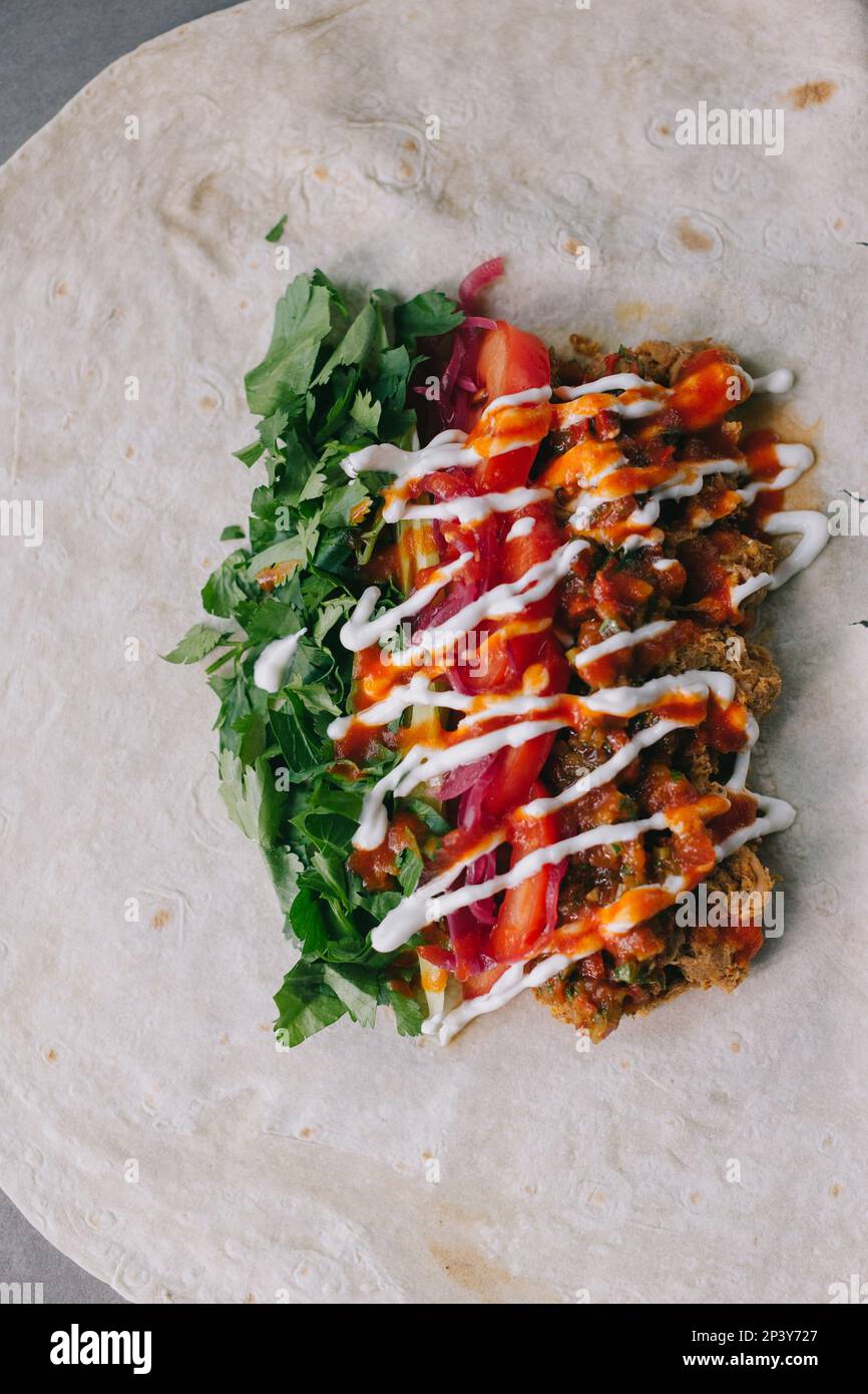 Shawarma-Vorbereitung. Fleisch, Gemüse und Soße auf Pita-Brot. Stockfoto