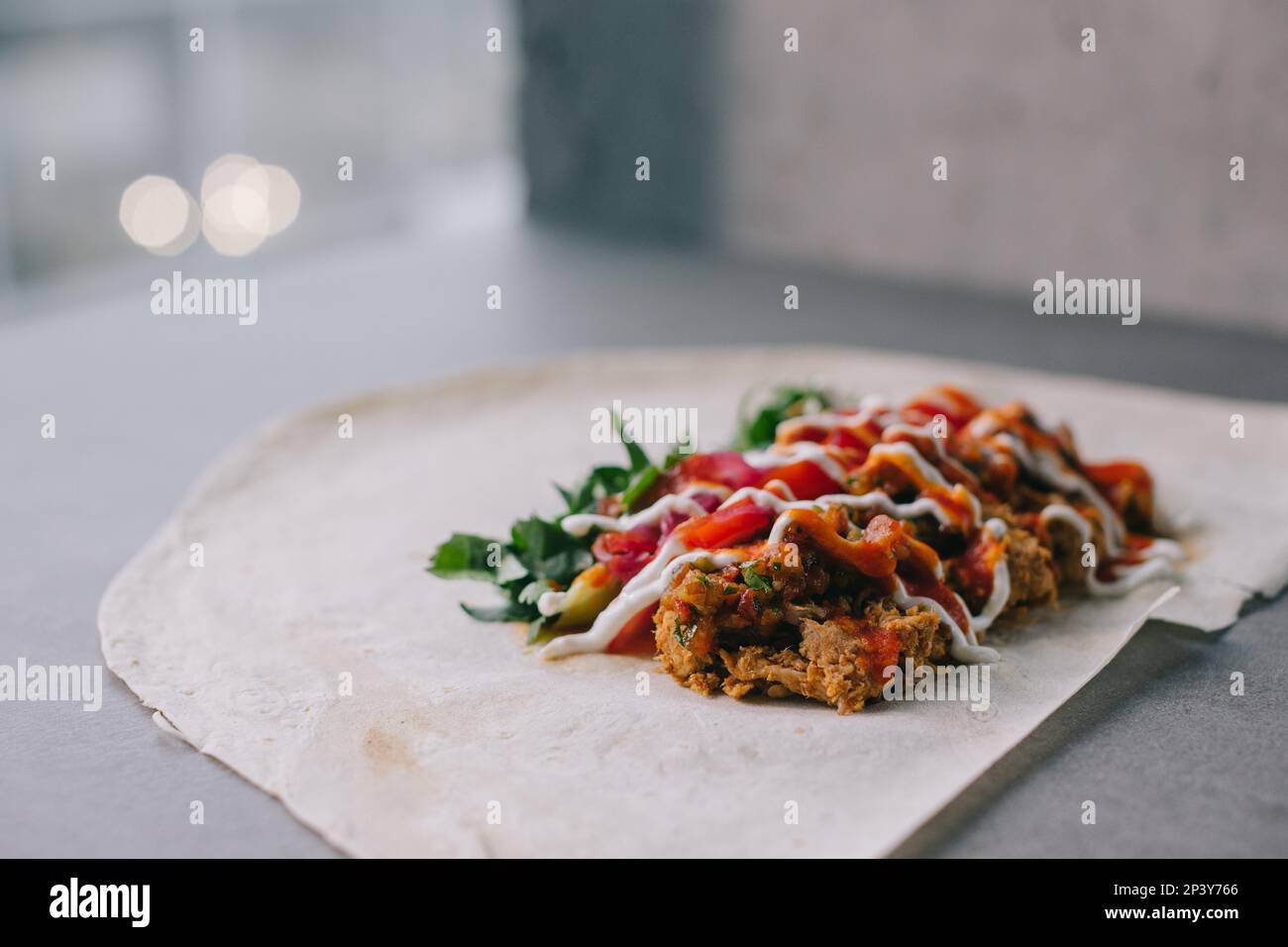 Shawarma-Vorbereitung. Fleisch, Gemüse und Soße auf Pita-Brot. Stockfoto