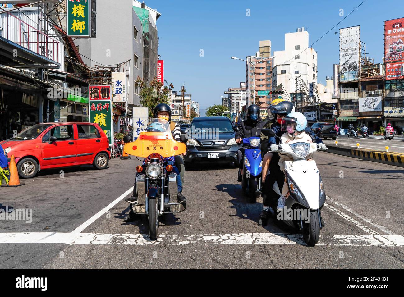Motorradfahrer unterhalten sich, während sie an einer Kreuzung in Taichung in einem Bereich sitzen, der für Fahrräder vorgesehen ist. Das tägliche Leben in Taichung, der zweitgrößten Stadt Taiwans. Um mehr internationale Touristen anzulocken, kündigte die taiwanesische Regierung kürzlich an, dass sie 5000 Taiwan-Dollar (ca. 165 USD) als Teil eines Konjunkturpakets zur Unterstützung der Reisesubventionierung für Touristen bereitstellen werde. Stockfoto