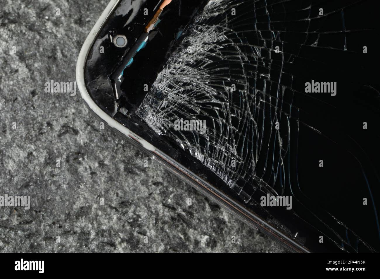 Smartphone mit rissigem Bildschirm auf grauem Steinhintergrund, Nahaufnahme. Gerätereparatur Stockfoto
