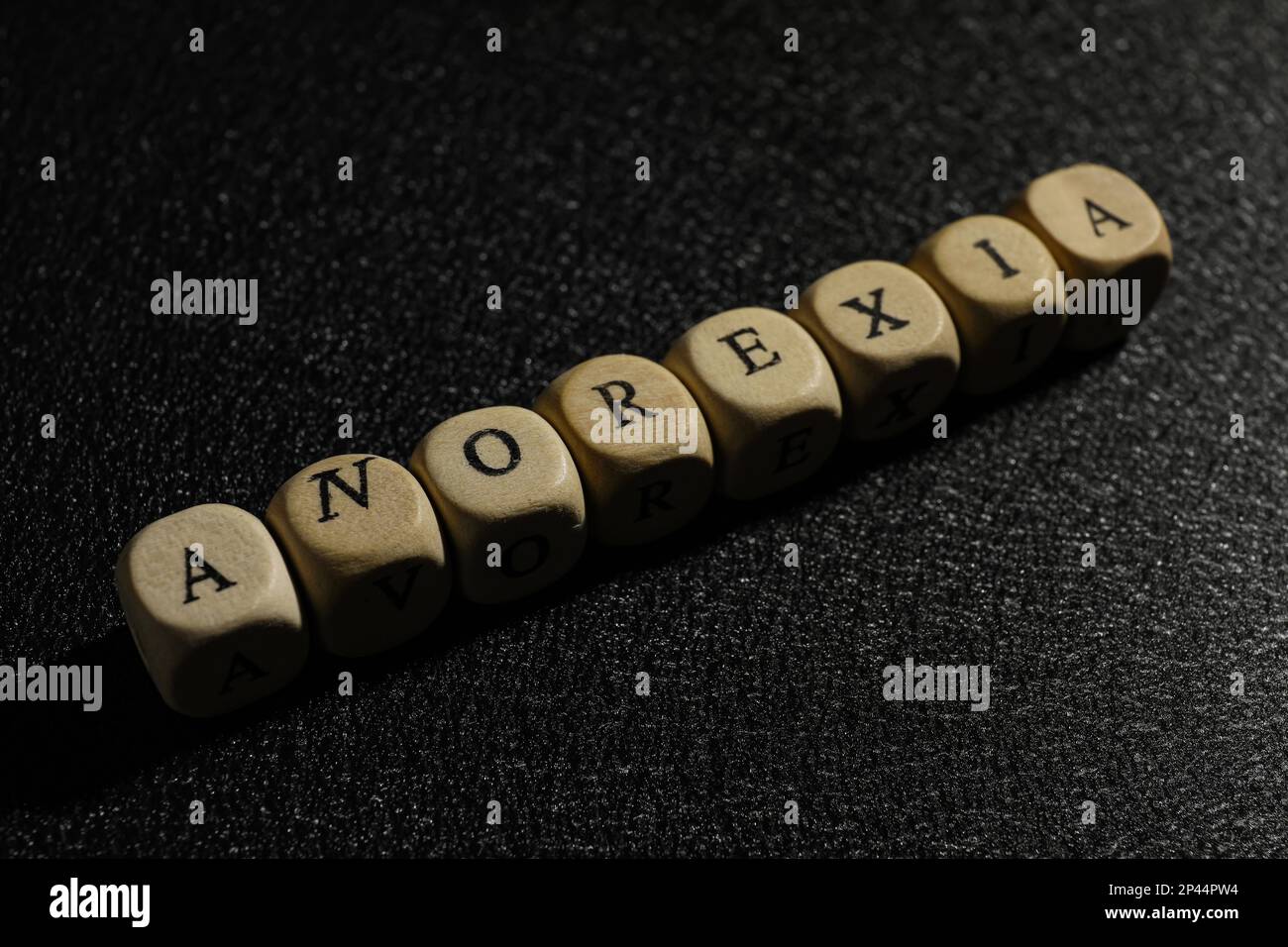 Das Wort Anorexia aus Holzwürfeln auf schwarzem Hintergrund, Nahaufnahme Stockfoto