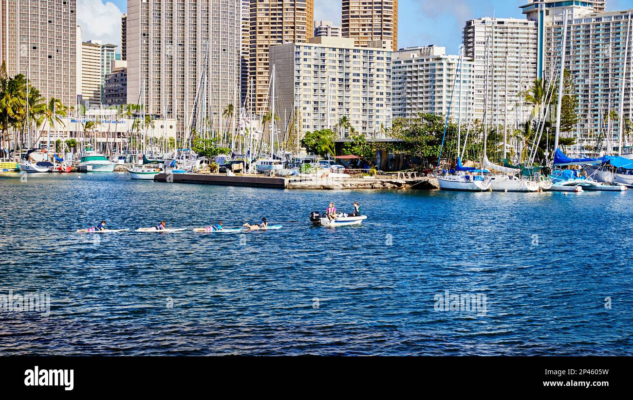 Honolu, Oahu, Hawaii, USA, - 6. Februar, 2023 Uhr: Menschen auf Surfbrettern, die von einem kleinen Motorboot im Hafen von Ilikai gezogen werden Stockfoto