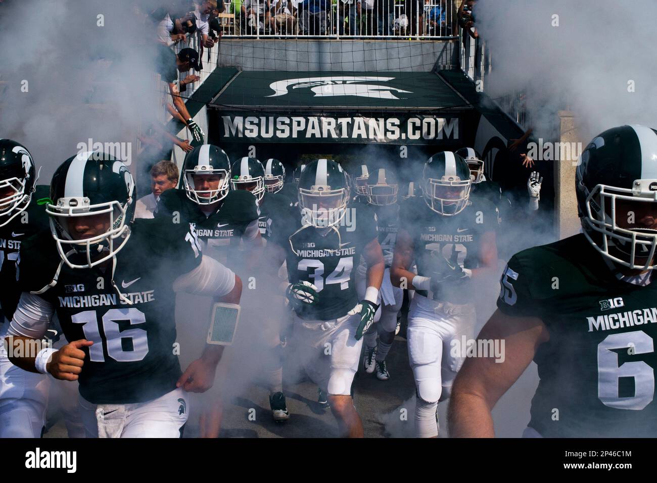 Michigan State's Tommy Vento, left, runs alongside his teammates as they take the field through a screen of smoke before playing Eastern Michigan on Saturday, Sept. 20, 2014 at Spartan Stadium in East Lansing, Mich. (AP Photo/The Flint Journal, Jake May) Stockfoto