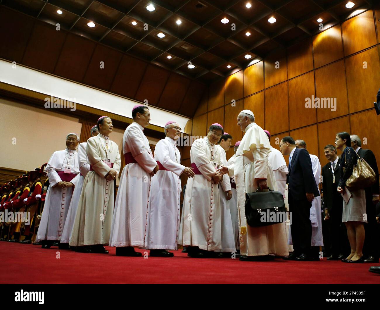 Pope Francis shakes hands with bishops before boarding his plane as he leaves for the Vatican at Seoul Air Base in Seongnam, South Korea, Monday, Aug. 18, 2014. Pope Francis wrapped up his first trip to Asia on Monday by challenging Koreans - from the North and the South - to reject the "mindset of suspicion and confrontation" that clouds their relations and find new ways to forge peace on the war-divided peninsula. (AP Photo/Kim Hong-Ji, Pool) Stockfoto