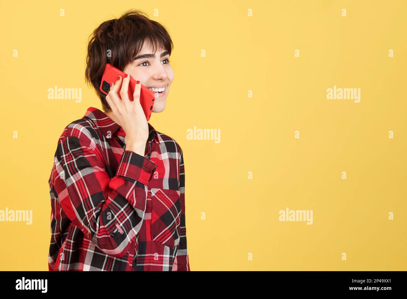 Glückliche androgyne Person, die mit dem Handy spricht Stockfoto
