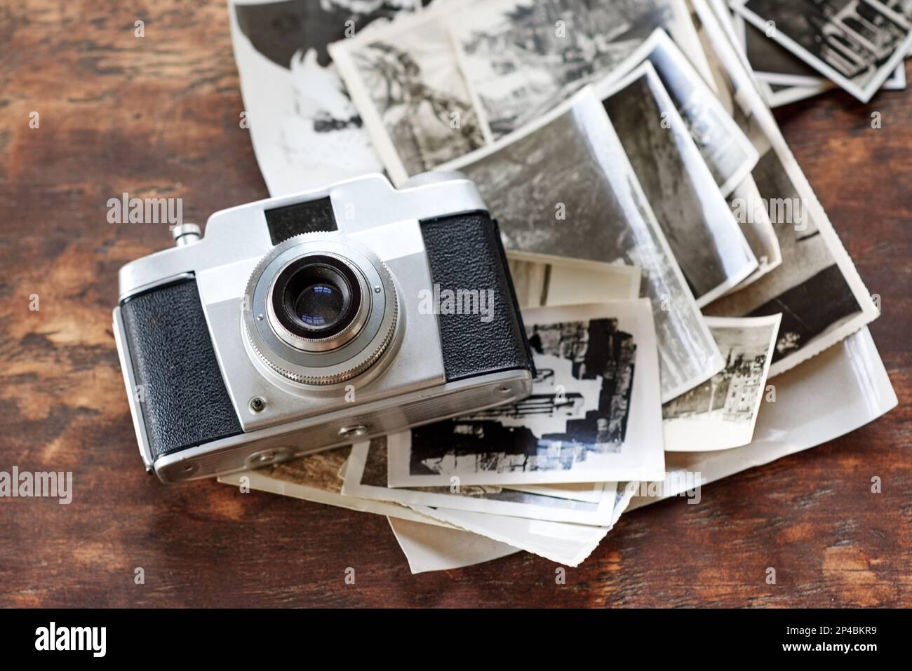 Unvergessliche Erinnerungen. Eine altmodische Kamera, die auf einem Stapel Schwarz-Weiß-Fotos liegt. Stockfoto