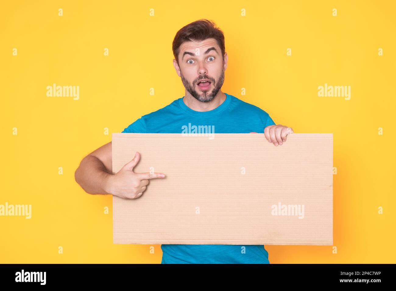 Der Mann hält ein Schild, eine leere Karte. Plakat für Ihr Produkt bereit. Unterschreib in deine SMS. Ein Mann zeigt leere Schilder über dem isolierten Studio-Hintergrund und zeigt auf ihn Stockfoto