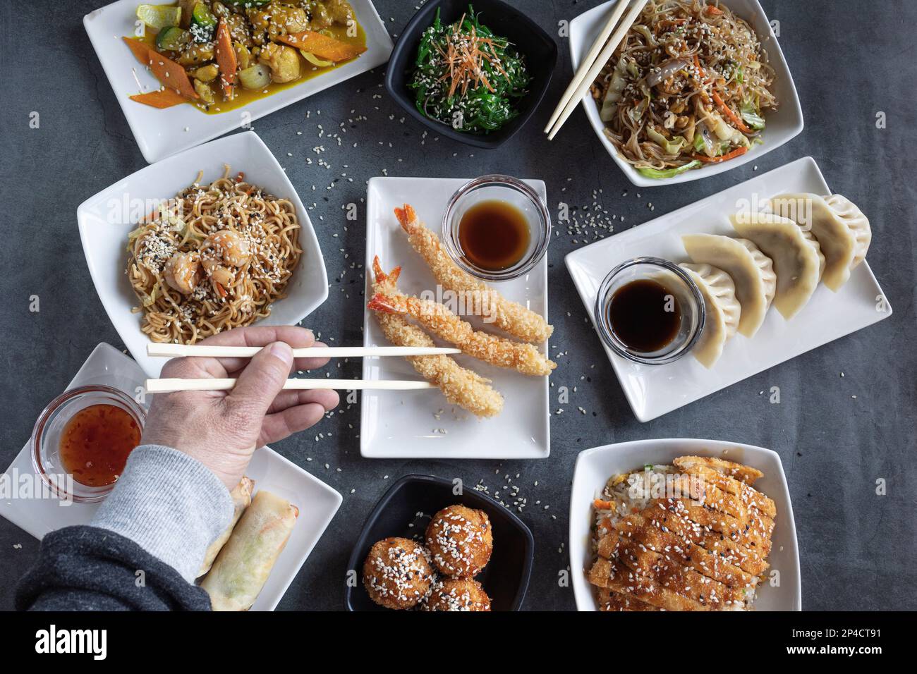 Blick auf Männerhände, die in einem orientalischen Restaurant mit Stäbchen essen. Stockfoto