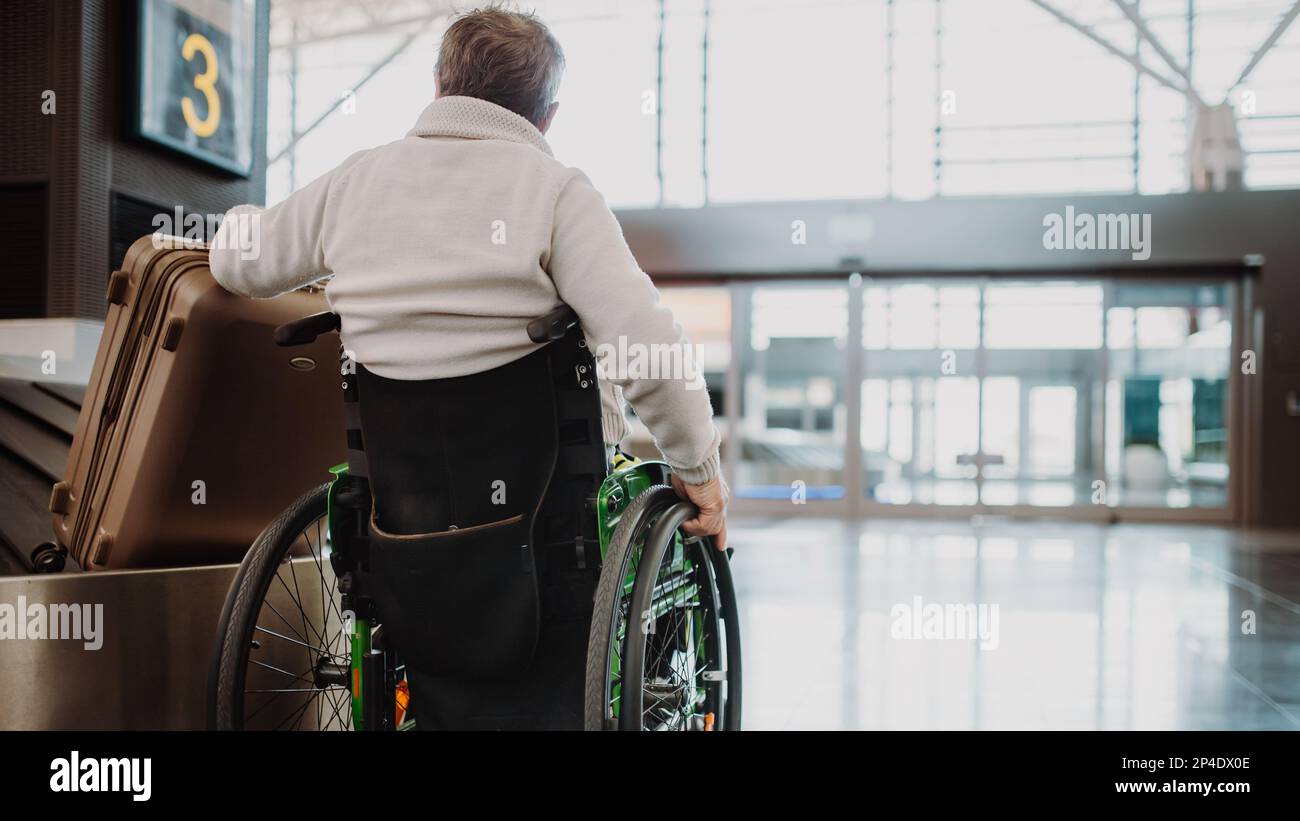 Rückansicht eines Rollstuhlfahrers am Flughafen mit seinem Gepäck. Stockfoto