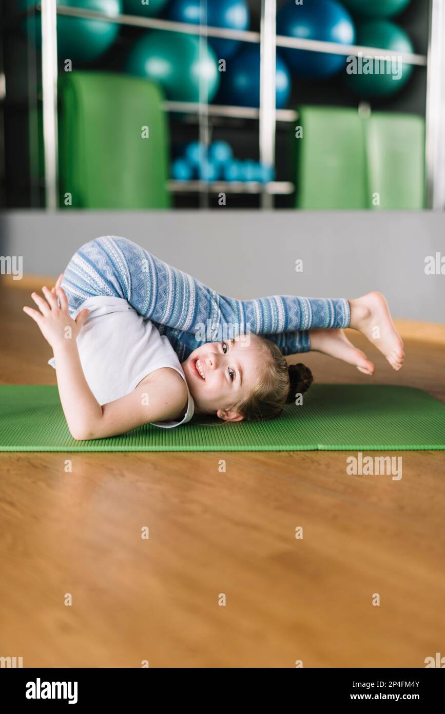 Glückliches Mädchen Kind praktiziert Yoga Matte suchen Kamera Stockfoto