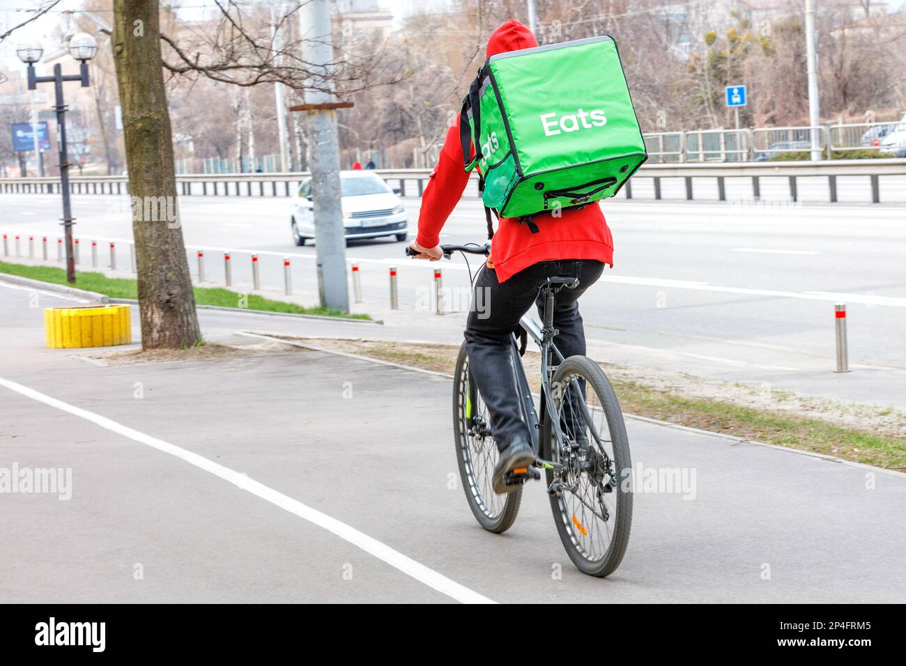 Mobile Lebensmittellieferung in der Stadt. Ein junger Mann auf einem Fahrrad liefert Essen in einem großen grünen Thermosack. Stockfoto