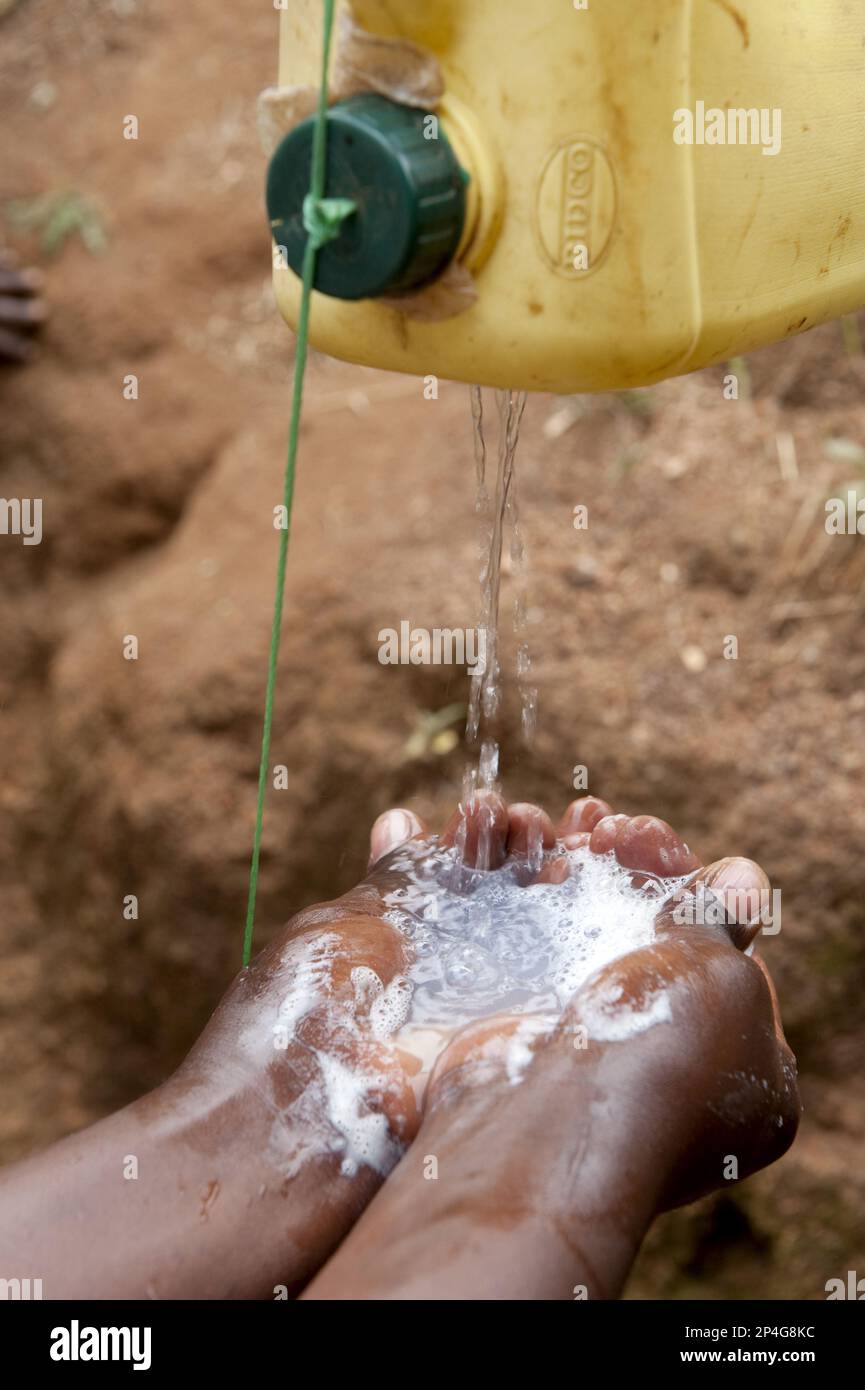 Hände waschen unter hausgemachtem Wasserhahn, Ruanda Stockfoto