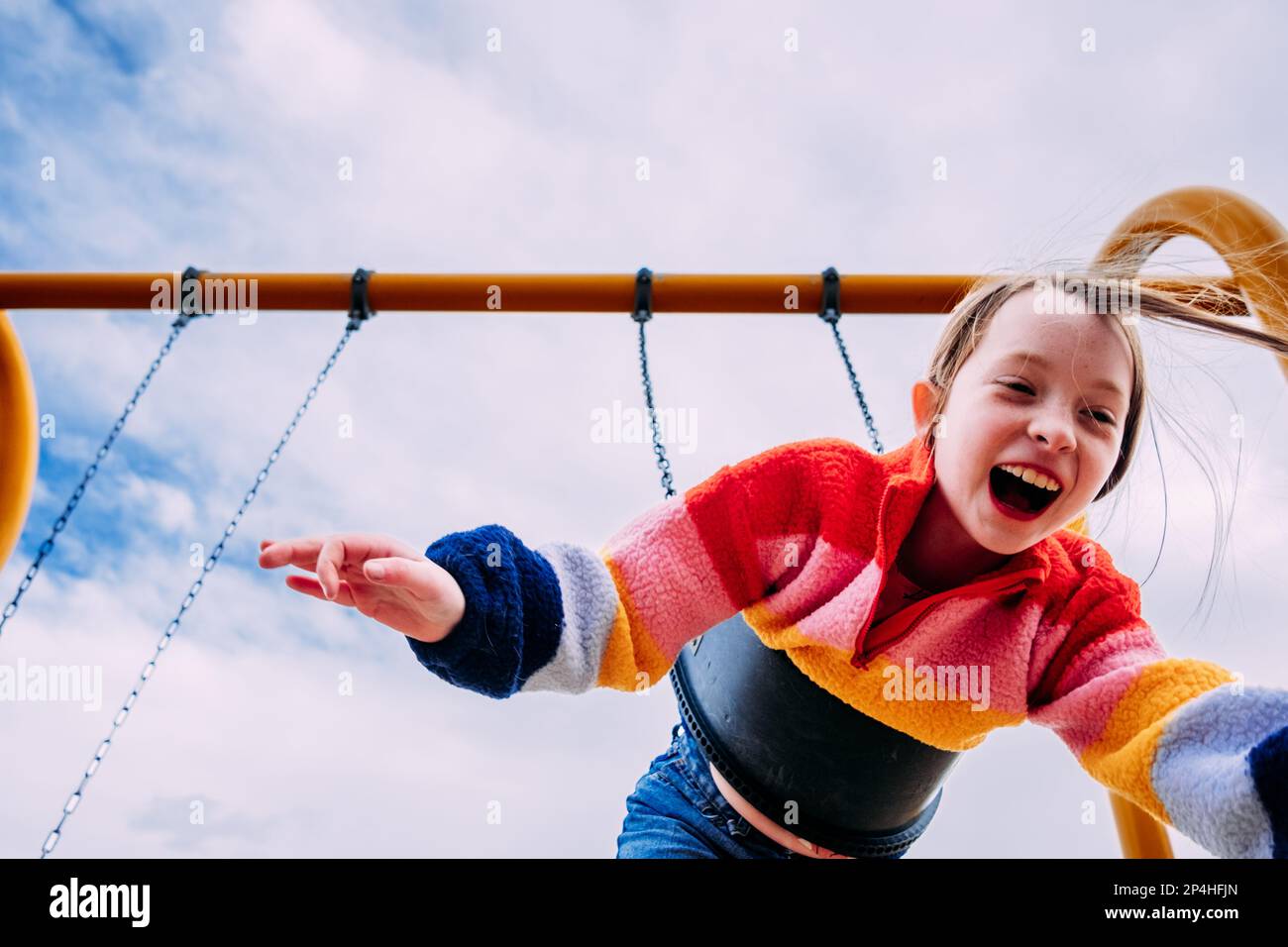 Ein Kind, das an einem bewölkten Tag auf der Schaukel spielt Stockfoto