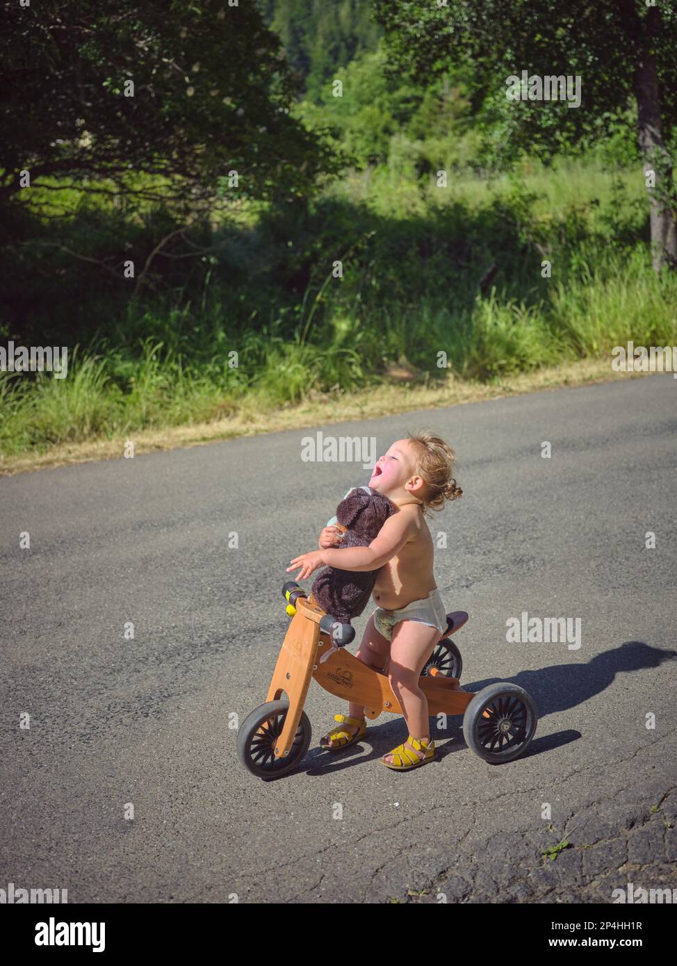 1 Jahre alt in Windeln ohne Kleidung, dreirädrig auf einer Landstraße Stockfoto