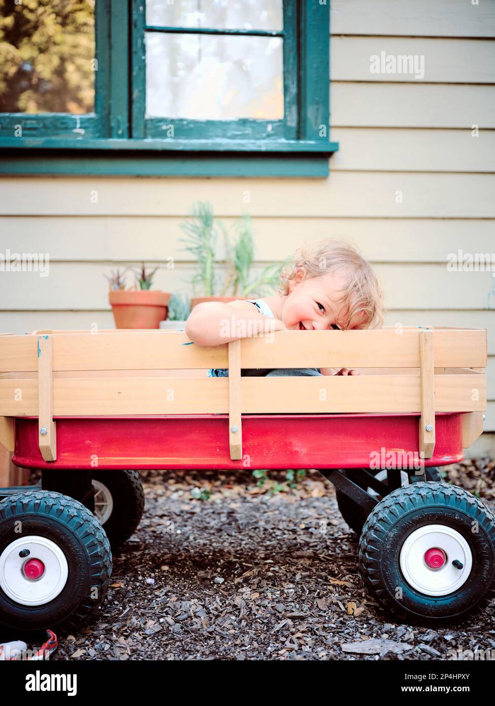 Ein Kleinkind lächelt im Radio Flyer Red Wagon, Marin, Kalifornien. Stockfoto