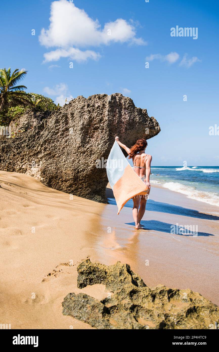 Alleinstehende Frau in einem Bikini mit Handtuch am Strand in Puerto Rico Stockfoto