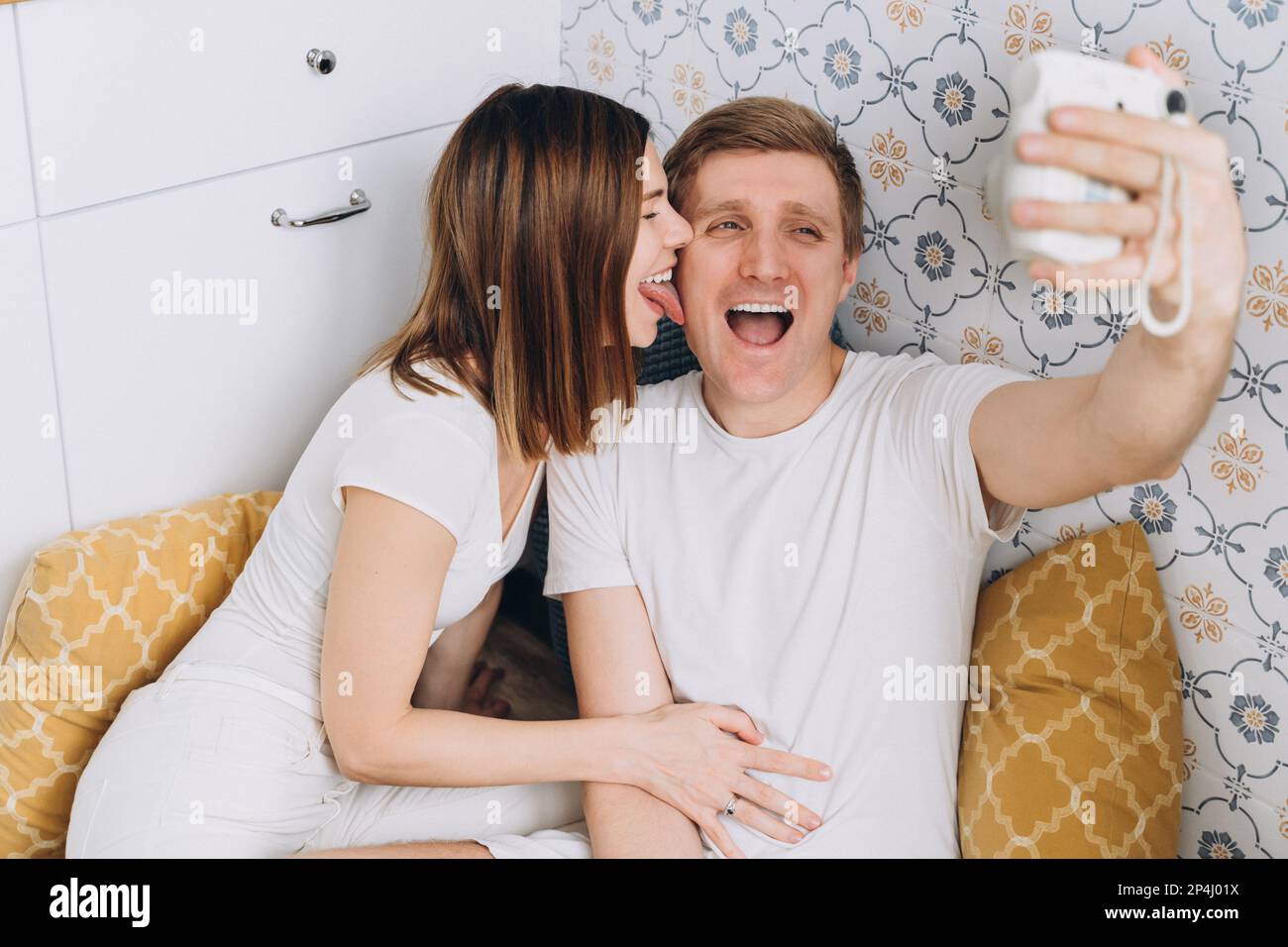 Ein Paar in der Küche macht ein lustiges Selfie mit einer Sofortkamera Stockfoto