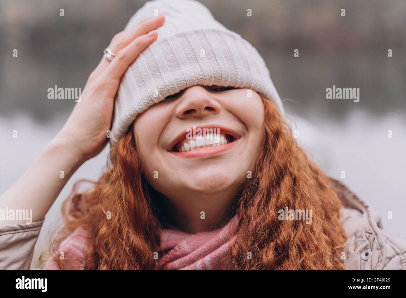 Lockige rothaarige Frau 30-35 mit einer Mütze über den Augen lacht Stockfoto