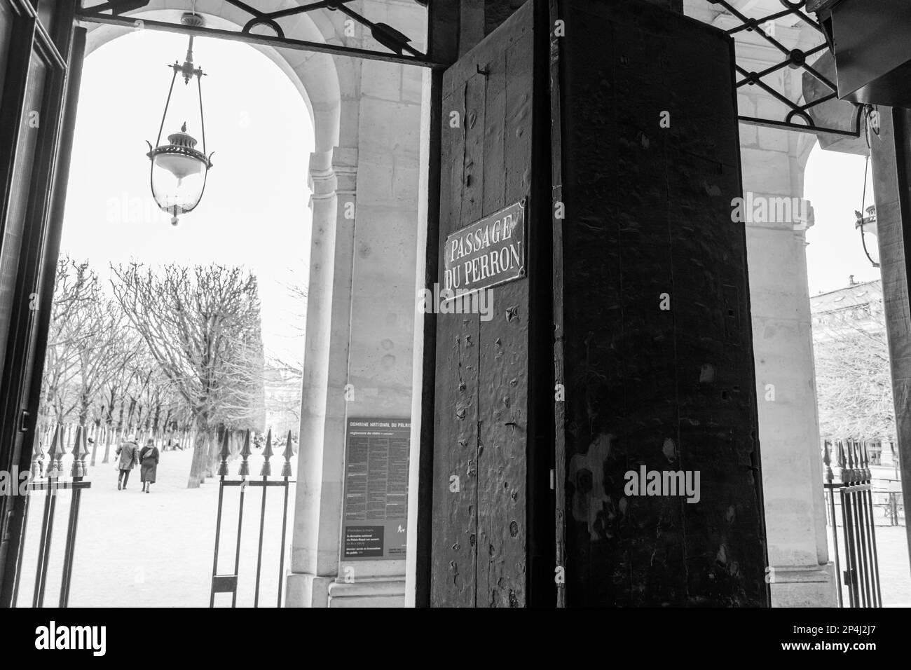 Schwarzweißfoto des Eingangs zum königlichen Garten des Palais von der Passage du Perron im 1. Arrondissement, Paris. Stockfoto