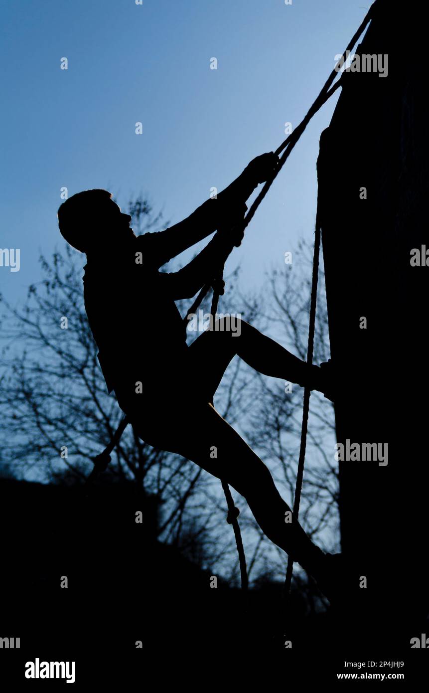 Ein Athlet klettert auf eine Wand eines Hindernisplatzes Stockfoto