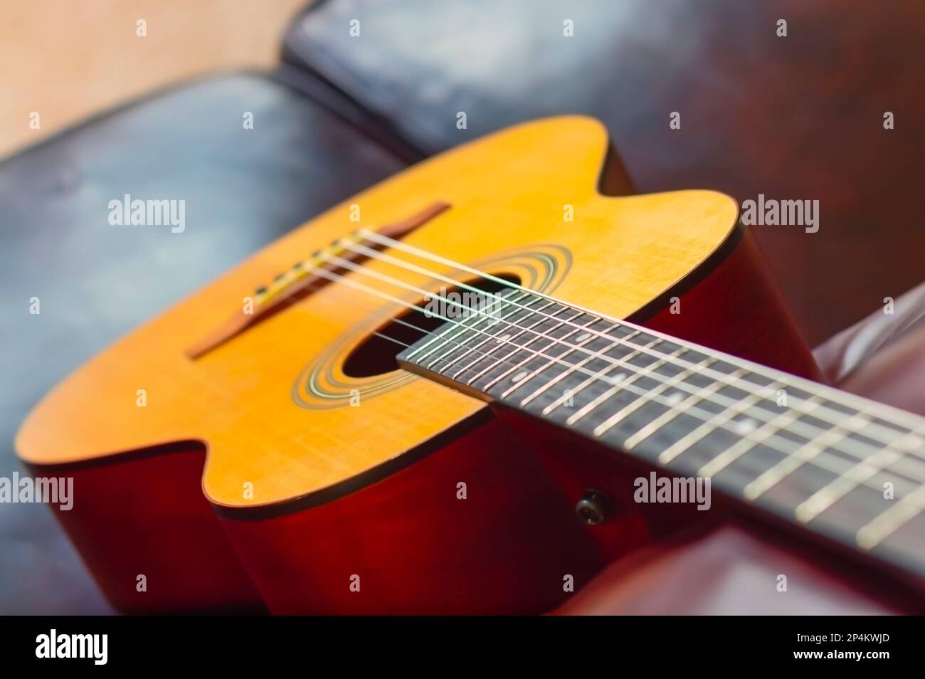 Eine Nahaufnahme der klassischen Akustikgitarre mit Nylonschnüren, die auf einer Couch liegt. Stockfoto