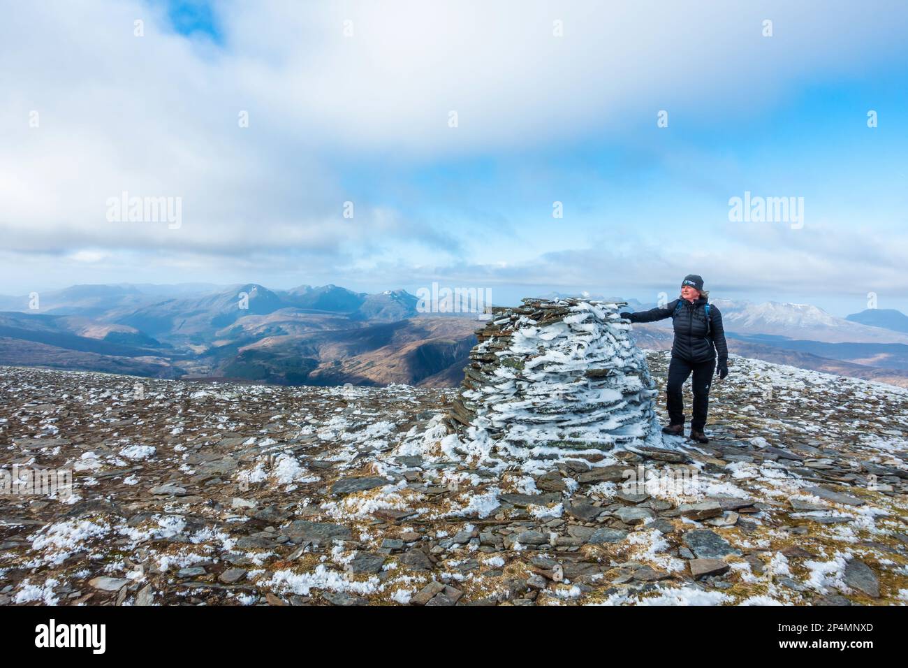 Ein Geher am Gipfelkairn auf dem Gipfel des schottischen Munro-Berges von Moruisg Stockfoto