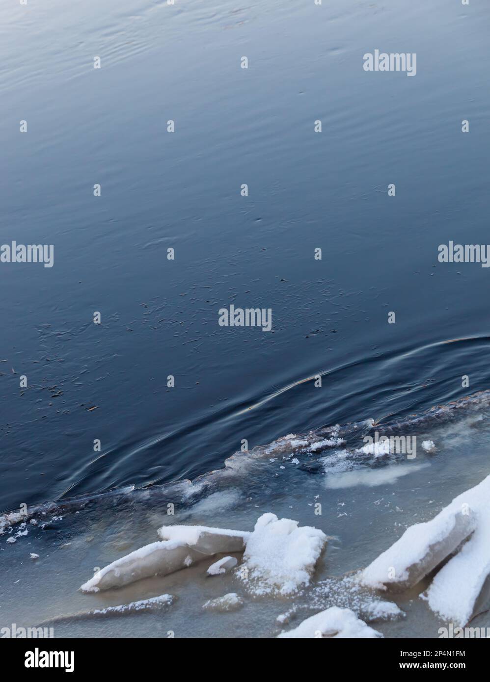 Riesige zerbrochene Eisblöcke liegen am Flussufer. Der dunkelblaue Fluss fließt über die Blöcke. Frühling. Hintergrund. Textur. Foto in hoher Qualität. Stockfoto