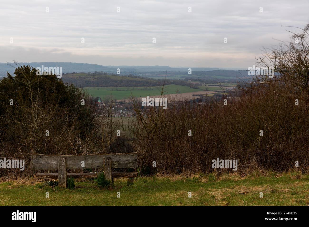Die Geisterfigur saß auf einer Bank mit Blick auf South Harting. Lange Belichtung an einem dunklen Tag, wodurch eine unscharfe Figur in sitzender Position entsteht. Die Umgebung ist scharf. Stockfoto