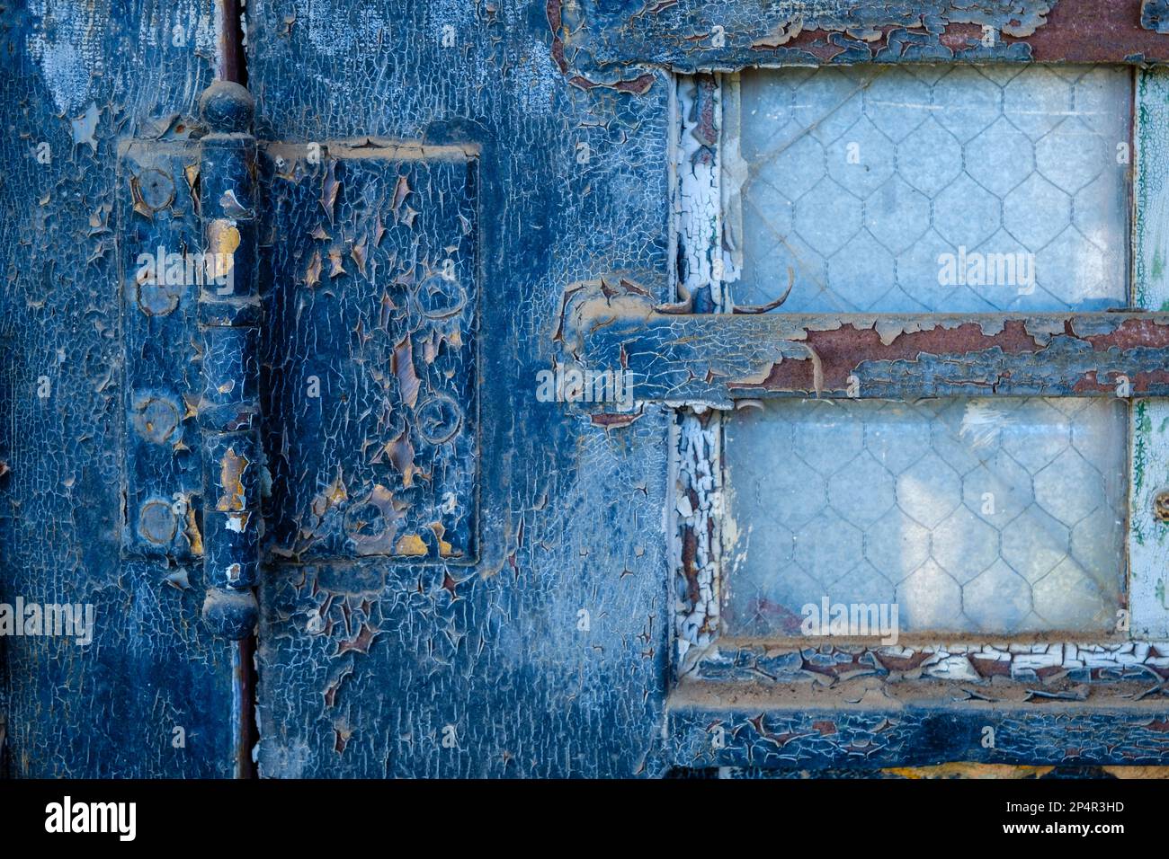 Blaue Farbe gerissen und verstärkte Witwe an der verwitterten alten Tür. Stockfoto