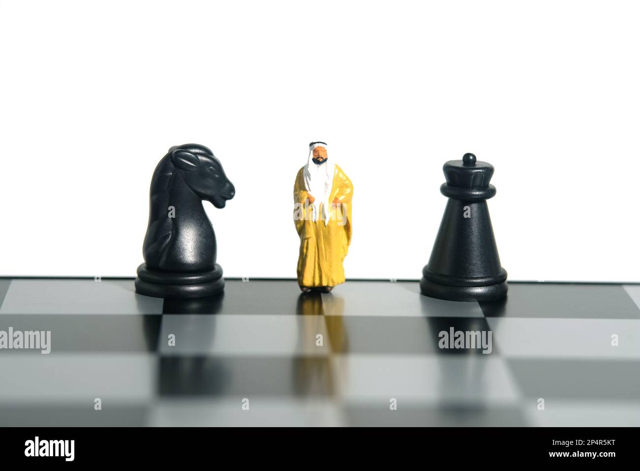 Miniatur-Menschen-Spielzeug-Figuren-Fotografie. Strategie für Verteidigungsangriffe. Ein Sultan, der über dem Schachbrett zwischen Pferd und Schachfigur steht. Stockfoto