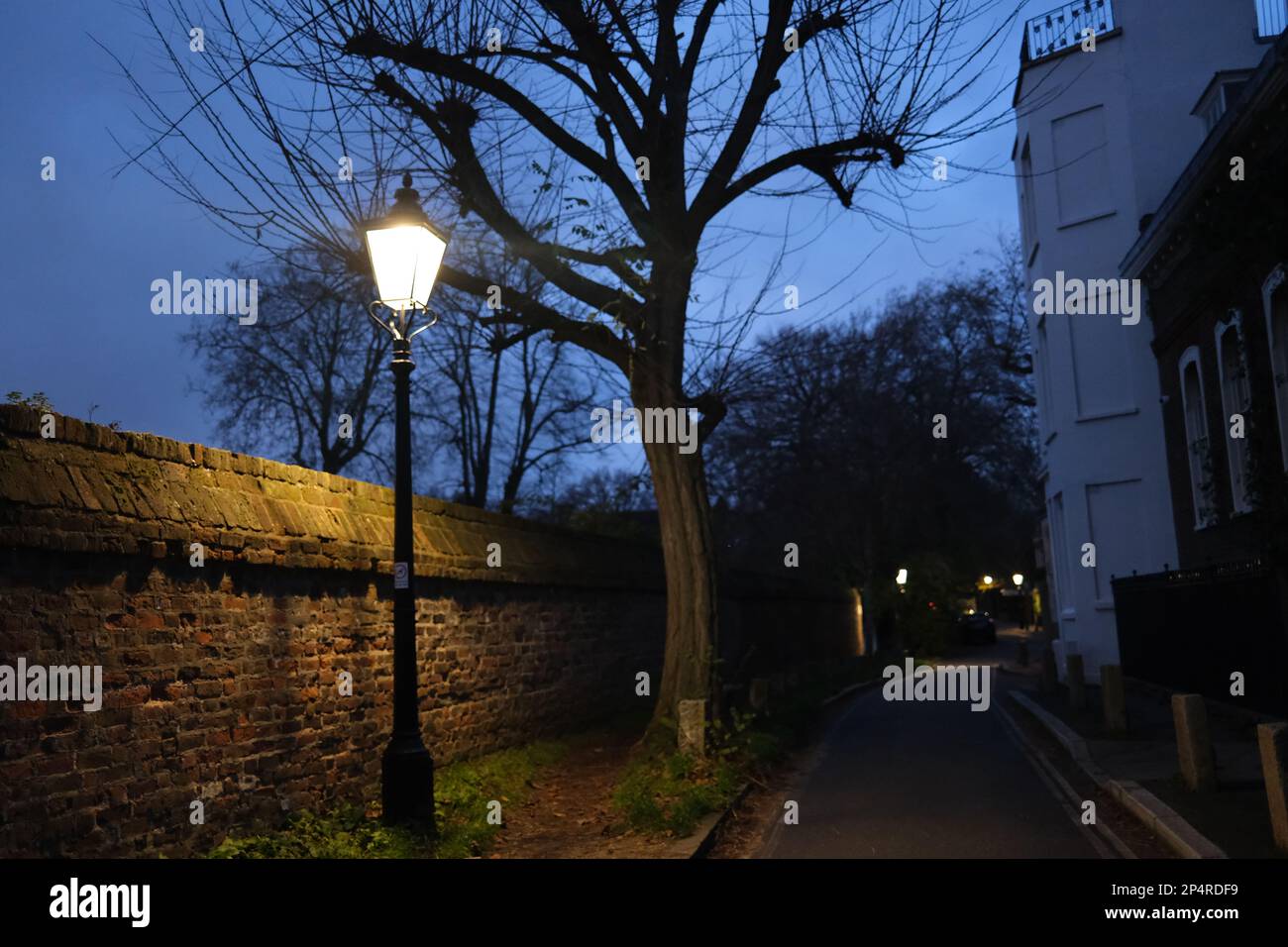 Eine dunkle und einsame Straße in Hampstead, Nord-London. Eine einzelne Lamelle beleuchtet eine kleine Umgebung. Stockfoto