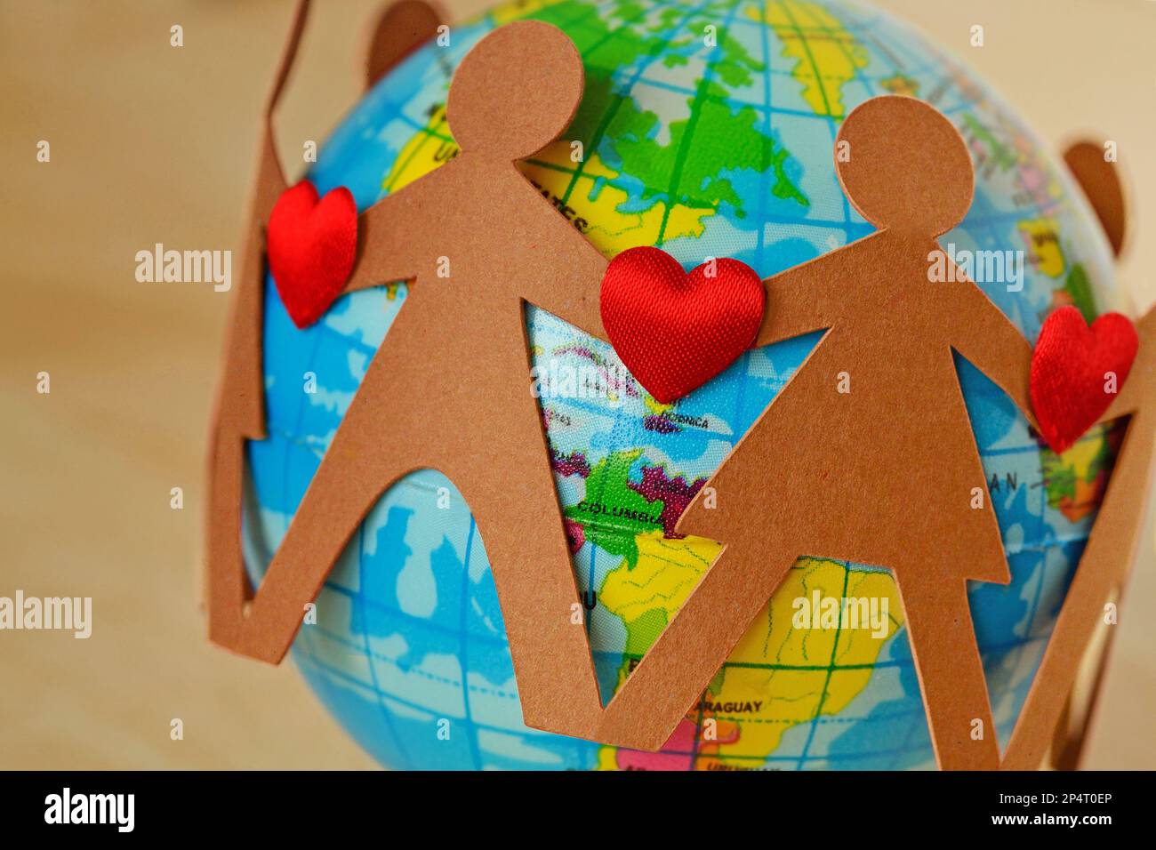 Papiermenschen mit Herzen im Kreis um den Erdball - Konzept der Liebe zum Planeten und Umweltfragen Stockfoto