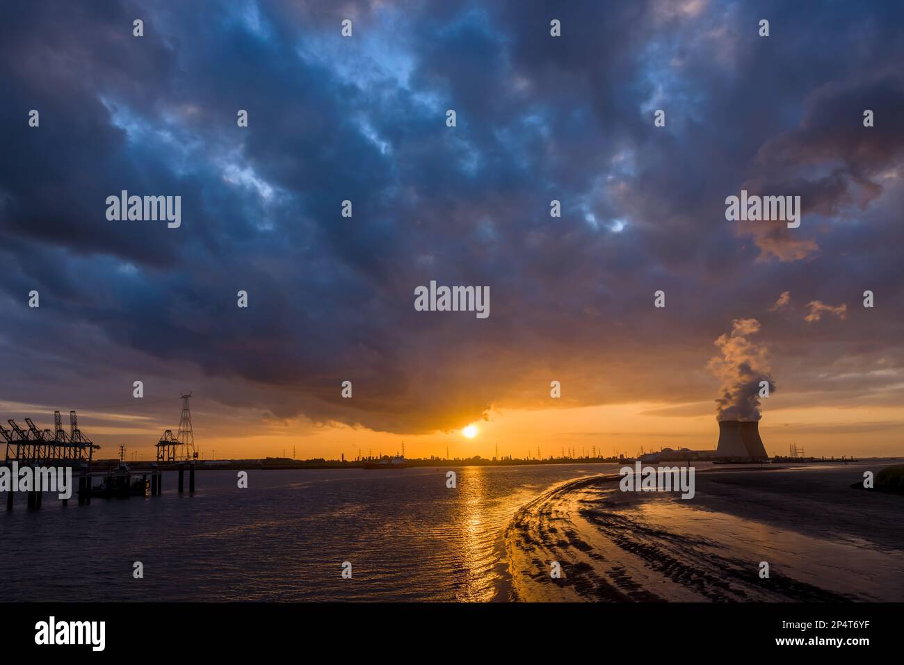 Farbenprächtiger Sonnenuntergang über dem Antwerpener Welthafen in Belgien mit Blick auf die Türme des Atomkraftwerks Stockfoto