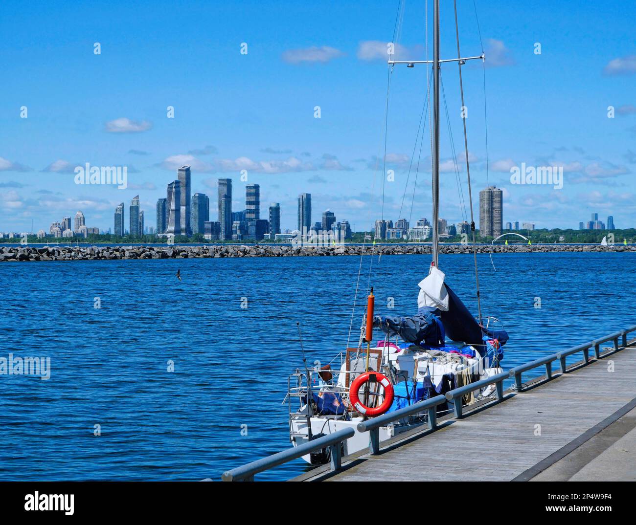 Lake Ontario mit Segelboot am Uferweg, mit Wolkenkratzern in einem Vorstadthaus von Toronto im Hintergrund Stockfoto