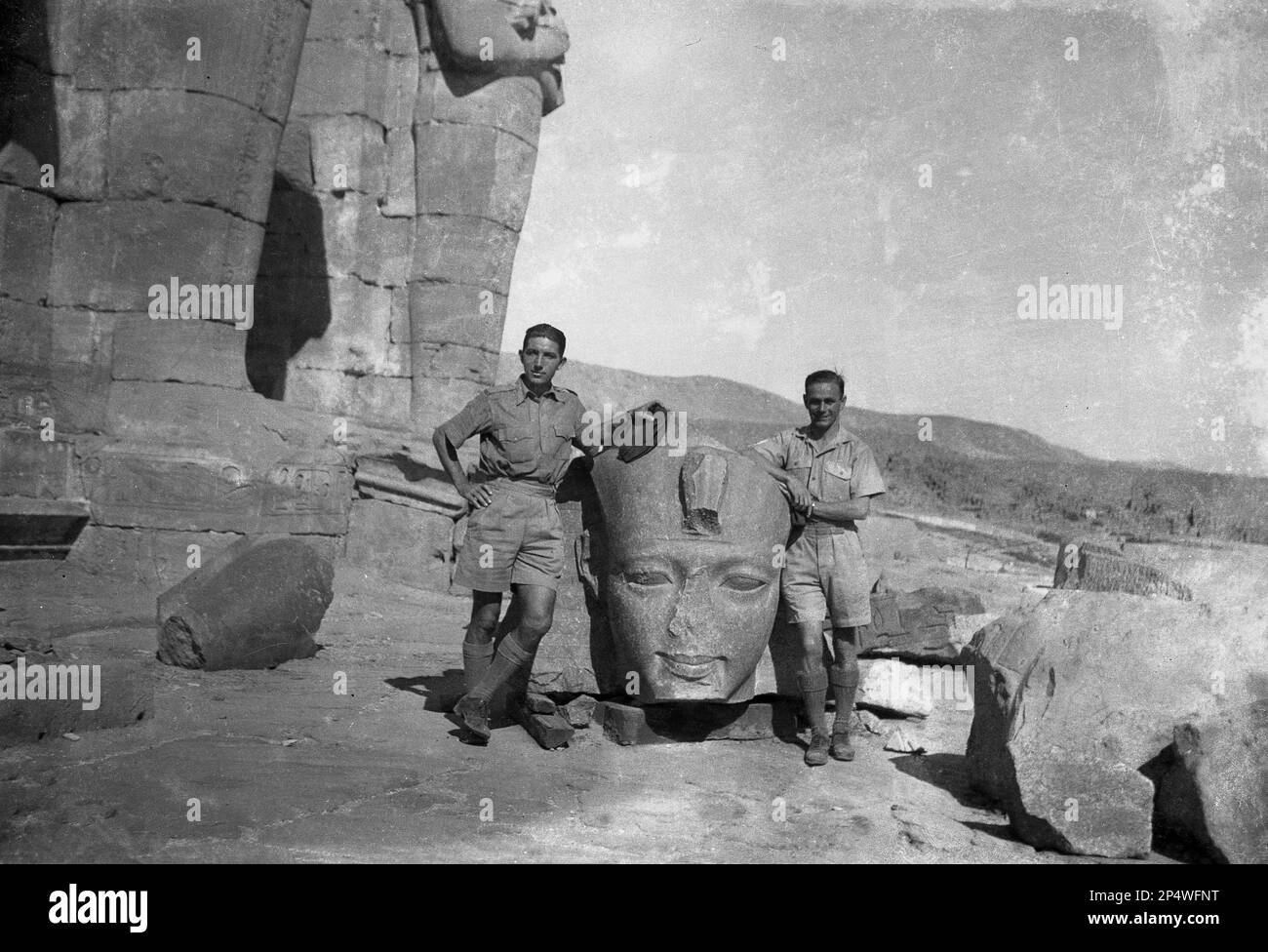1940er, historisch, zwei britische Soldaten stehen für ein Foto neben einer Statue eines pharaokopfes, an den antiken Ruinen des Tempels von Karnak, Luxor, Ägypten. Die ägyptischen Ruinen von Karnak sind ein antiker Gottesort, der als größte religiöse Stätte der Welt gilt und der Ort sein soll, an dem der gott Amun mit den Menschen der Erde verbunden ist. Stockfoto