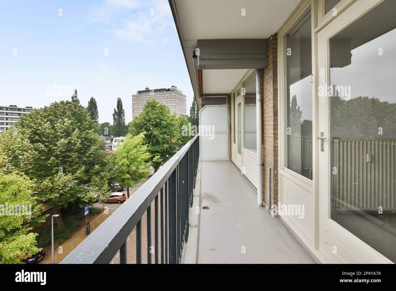 Amsterdam, Niederlande - 10. April 2021: Ein Backsteingebäude an der Seite einer Straße mit Autos, die vor dem Hotel geparkt sind und hinter denen Bäume den Bürgersteig säumen Stockfoto