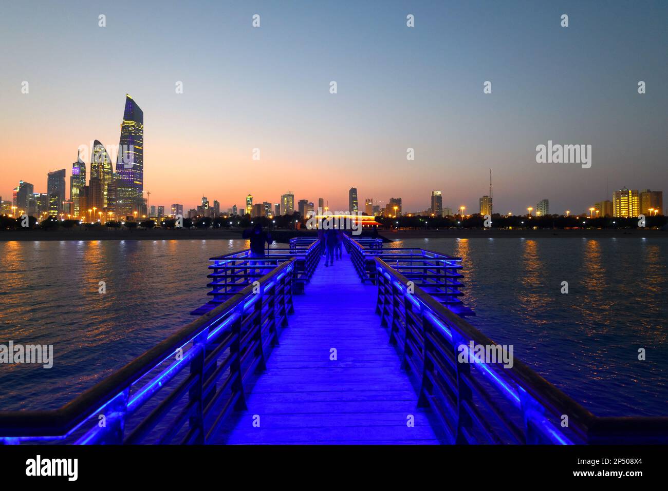 Kuwait City moderne Skyline vom öffentlichen Pier aus nach Sonnenuntergang zu sehen. Skyline von Kuwait mit Licht an. Stockfoto
